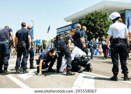 STRASBOURG, FRANCE - JULY 11, 2015: Police arresting man - Uyghur human rights activists participate in a demonstration to protest against Chinese government's policy in Uyghur