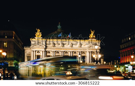 PARIS, FRANCE - JANUARY 22, 2013: City Bus and Taxi passing in front of the Palais Garnier - Opera Garnier & The National Academy of Music -  illuminated at night in Paris, France
