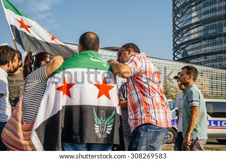 STRASBOURG, FRANCE - AUG 20, 2015: People protesting in front of European Parliament denouncing the Syrian airstrikes on Douma wheremore 80 were killed - people holding wearing Syrian flag