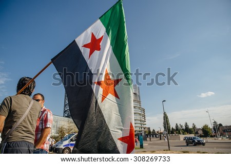 STRASBOURG, FRANCE - AUG 20, 2015: People protesting in front of European Parliament denouncing the Syrian airstrikes on Douma wheremore 80 were killed - man holding flag of Syria