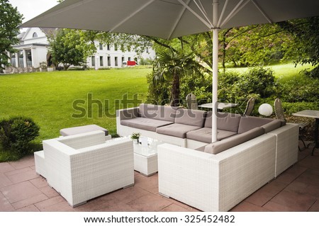 Luxury modern fashioned patio cafe lounge with umbrella and comfotable chairs in green park