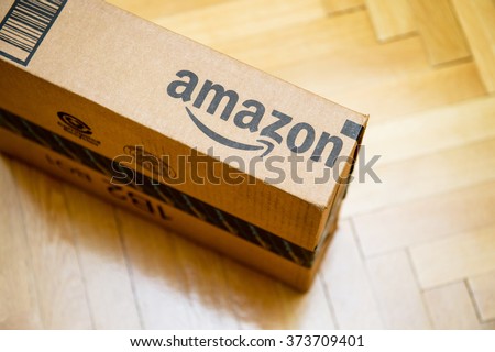 PARIS, FRANCE - JAN 28, 2016: Amazon logotype printed on cardboard box side seen from above on a wooden parwuet floor. Amazon is an American electronic e-commerce company distribution worlwide