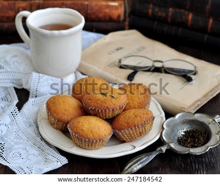 Cakes of handwork with the dried cranberry and tea, ancient books, glasses on an ancient dinner-table