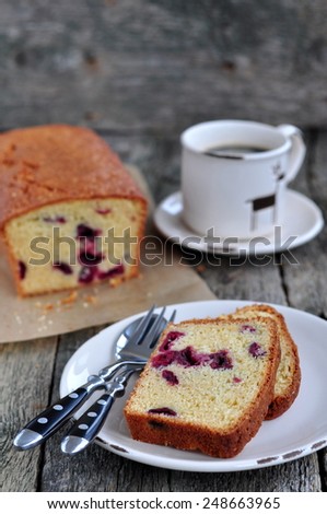 Cup of coffee or tea with a cherry cake on a wooden dinner-table