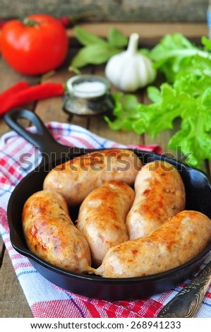 fried chicken sausages with vegetables on a frying pan. selective focus.