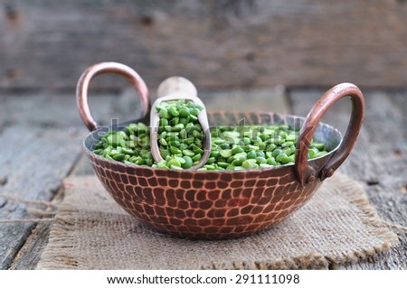 Dried green split peas in a copper plate on a wooden table
