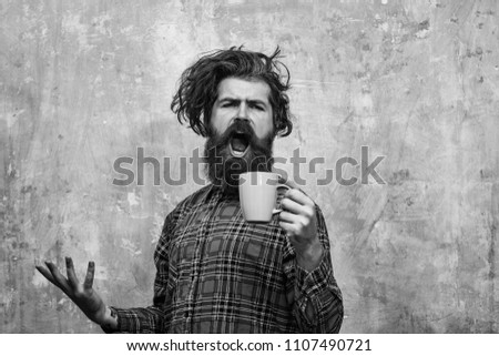 Morning coffe. singing bearded man, caucasian hipster, with long beard and moustache pulling stylish fringe hair, haircut, in red plaid shirt with blue cup on abstract pink wall background