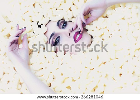 Fashionable woman with bright make-up lying in corn sticks heap