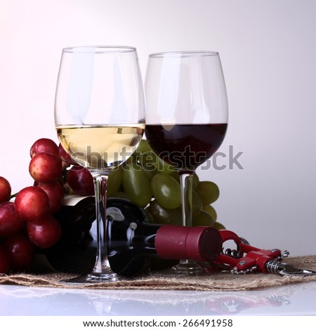 Glasses of red and white wine, bottle and grape on light background