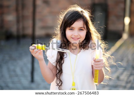 Charming little girl smiling and making soap bubbles, horizontal picture