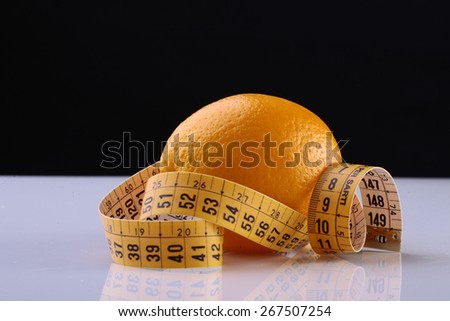 Orange fruit and measuring tape on white table on black background