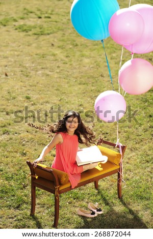 Cute little girl on the bench holding a sketch-book, vertical picture