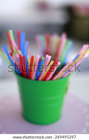 Multicolored straws yellow pink blue green purple orange and red colors in little bucket closeup, vertical picture