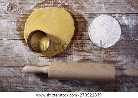 Ingredients for making pastry with flour rolled dough and mould for baking on wooden table top in flour, horizontal picture
