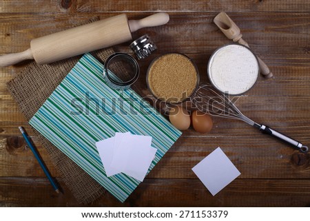 Set of ingredients and appliances for cooking with closed recipe book on wooden table top, horizontal picture