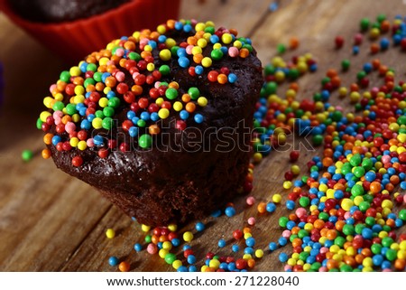 Chocolate cup cake and candy colored icing yellow red blue orange pink green color closeup, horizontal picture