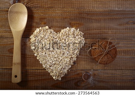 Oatcakes and heart shapes oatmeal and wooden spoon on wooden table top, horizontal picture