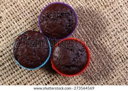 Chocolate cupcakes on sacking in colored silicone bakewares violet blue and red colors copyspace, horizontal photo