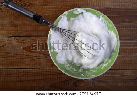 Frothed eggs in foam by beater on green plate copyspace, horizontal photo