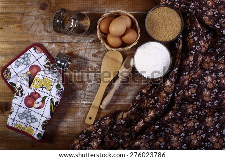 Ingredients and appliances for cooking with eggs flour brown sugar on wooden table top with table cloth, horizontal picture