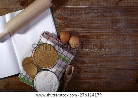 Set of ingredients and appliances for cooking with opened recipe book and towel on wooden table top copyspace, horizontal picture