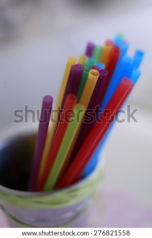 Colorful straws yellow pink blue green purple orange and red colors in little bucket closeup, vertical picture