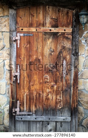 Wooden brown door with metal finish in a wall of masonry in vintage style, vertical picture