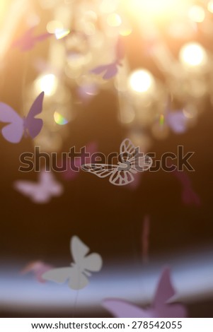 Shiny violet decorative butterflies hovering under the light, vertical photo