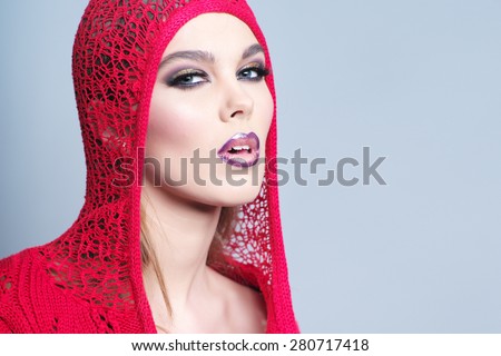 Alluring sexual young woman in red knitted jacket with bright make up and beautiful slim body looking forward standing on grey wall background copy space, horizontal picture