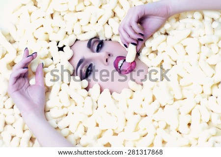 Portrait of sexual young beautiful girl face in corn sticks heap tasting and looking forward on light food background copy space, horizontal picture