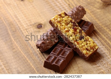 Sweet chocolate bars and peanut brittle on brown wooden table top background copy space, horizontal photo