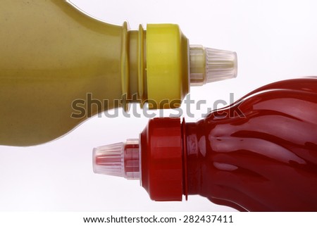 Bright red and dark yellow bottles of ketchup and mustard on a white background closeup, horizontal photo