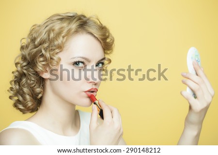 Attrective woman in a white dress rouges with lipstick