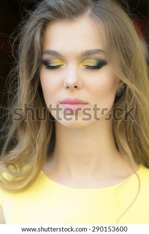 Portrait of dreaming sensible young blonde lady with bright makeup and curly hair and closed eyes, vertical background