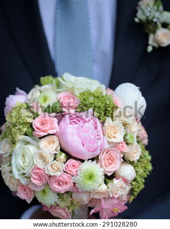 Bridegroom holding beautiful fresh wedding bouquet of pink lilac purple white and violet chrysanthemum rose and peony flowers closeup, vertical picture
