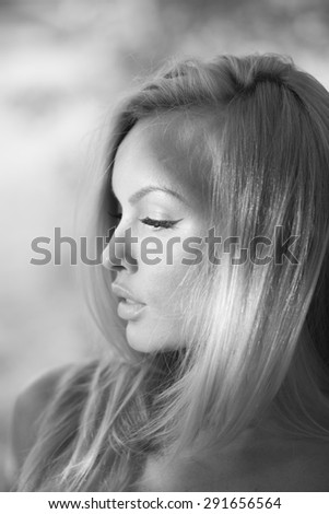 Profile of young pretty woman with silk hair on natural background black and white closeup, vertical picture