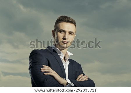 Strong successful man in formal suit with bow tie standing on bluesky background, horizontal picture