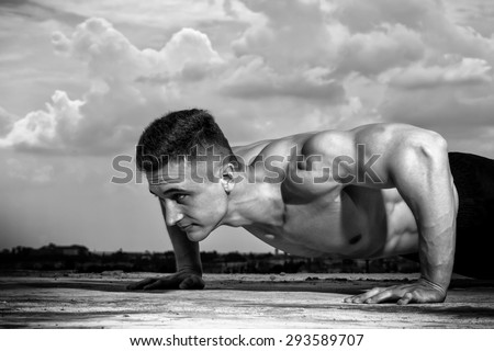 Beautiful sexy muscular naked male bodybuilder sports on sky background black and white, horizontal picture