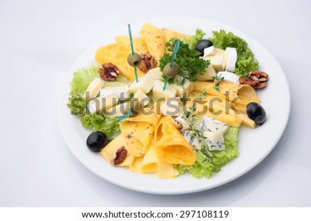 Mixed cheese diner platter from different varieties of cheese decorated with olives walnuts lettuce parsley isolated on white, horizontal picture
