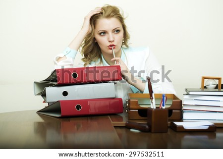 Pretty thoughtful working business woman sitting in office at table with many documents books files folders has a lot of work holding pen on white background, horizontal picture
