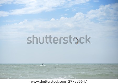 Beautiful view on ocean water with horizon line and bright blue sky sunny day and paraglider with paraplane surfing on natural background, horizontal picture