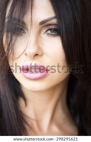 Portrait of attractive sexy young lady with hard look bright makeup plump ripe lips long neck and black hair looking forward closeuo, vertical picture