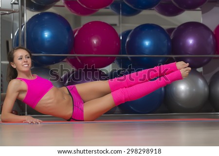 Sexy beautiful slim sporty fitness girl in pink with flexible body stretching lying on floor in training hall on sport balls background, horizontal picture