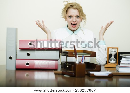 Pretty young crazy secretary girl with curly hair has stress sitting at table with many folders documents and office appliances shouting on white background, horizontal picture