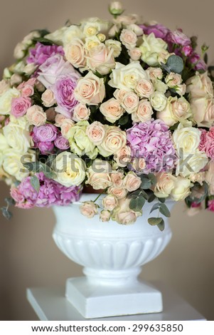 Decorate wedding bouquet of fresh beautiful flowers of roses and peony white pink violet purple yellow lilac and orange colours in big vase on beige background, vertical picture