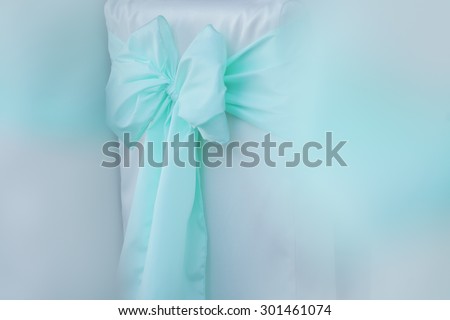 Closeup of decorative light blue bow tie ribbon of soft veil fabric in pastel shades with white color copyspace, horizontal picture