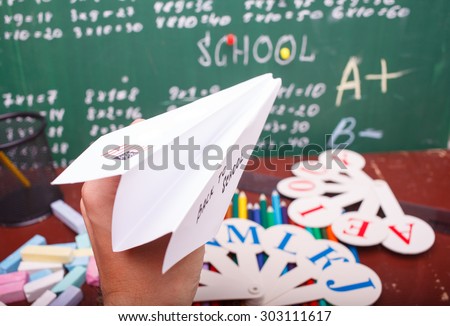 Colorful pencils of red yellow orange violet purple pink green and blue stationary cup ruler fan english alphabet and paper plane with back to school text written with white chalk blackboard on math