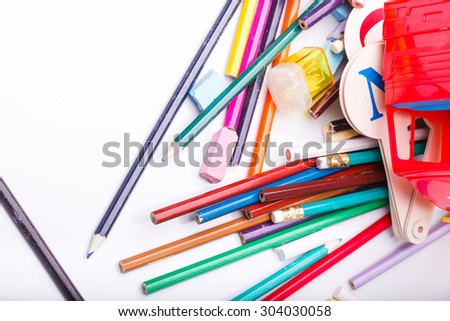 Colorful pencils of red yellow orange violet purple pink green blue chalk fan english alphabet and truck car toy lying on white school desk background, horizontal photo