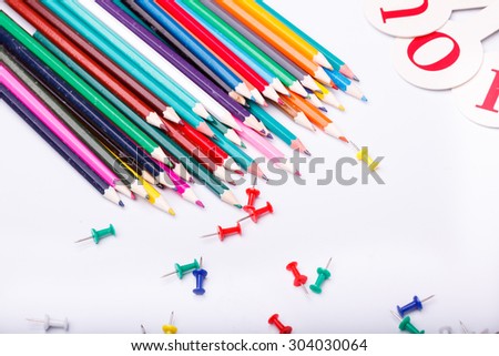 Colorful pencils of red yellow orange violet purple pink green blue chalk and fan english alphabet with capital letters lying on white school desk background copyspace, horizontal photo