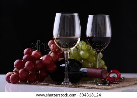 Closeup of two glasses with red and white wine standing on burlap napkin near green and red grapes bunches and lying new uncorked bottle and corkscrew on black background, horizontal picture